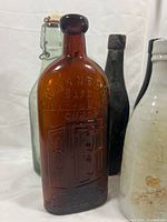 Front view showing embossed amber Warner’s bottle, green bail soda bottle, dark bottle behind