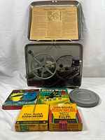 Projector in open case with six film reels displayed