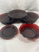 Stacked ruby red pressed glass plates, fluted bowl and small plate visible