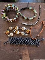 Top view of 5 assorted bracelets on wooden surface showing colors and bead details