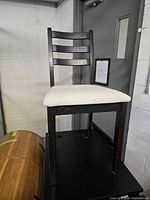 Full view of the dark wooden chair with white upholstered seat showing overall appearance and condition.