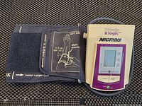 Photo of the blood pressure monitor and attached cuff showing the display and cuff labeled for left arm placement.