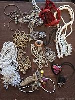 Top view of assorted necklaces on wooden surface, showing variety of materials and styles including beads, metal chains, velvet ribbon, and pendants.