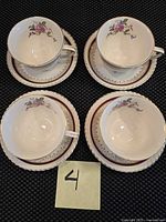 Top view of four cups on matching saucers showing floral pattern and burgundy borders with gold trim