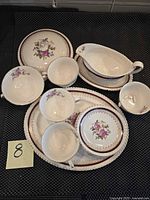Full set of dishes arranged including gravy boat, plates, bowl, cups, saucers, and cover, showing pattern and quantity