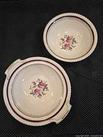 Two Johnson Bros ceramic serving bowls with floral Old English decoration. One smaller round bowl and one larger bowl with handles. Both bowls have maroon and gold accents.