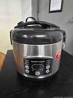 Hamilton Beach rice cooker outer unit with lid closed, digital control panel visible on front.