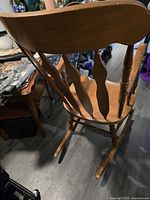 View of the rocking chair from an angle showing the curved backrest with four vertical slats and turned legs.
