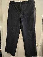 Black vintage trousers laid flat, showing full length and zipper fly