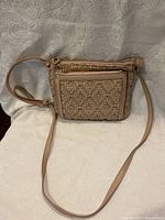 Front view of a natural tone leather crossbody purse showing the woven leather detail on the front pocket with the strap