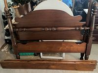 Front view of the antique black walnut footboard showing turned posts and spindle detail.