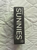Black original packaging showing 'Stonz Sunnies Sport' branding of baby sunglasses.