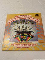 Front cover of The Beatles Magical Mystery Tour vinyl album showing colorful psychedelic design with band in animal costumes and rainbow banner
