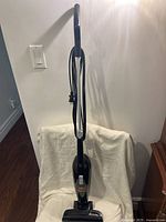 Front view of the Bissell Magic Vac vacuum cleaner standing upright, showing handle, power button, and cord wrapped around the back.