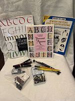 Photo showing the collection of Sheaffer dip pens, ink bottles, assorted nibs in plastic containers, and three books on calligraphy and artistic motifs