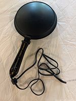 Full view of the electric crepe maker showing cooking surface, handle, and power cord.