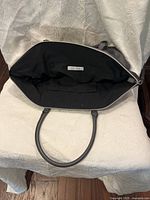Open purse showing black interior lining and zipper pocket with Kenneth Cole Reaction label.