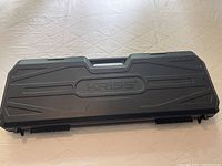 Closed black Kriss hard case with embossed KRISS logo and carry handle, showing top surface and latches.