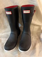 Front view of black Hunter rubber boots with red interior lining and white soles.