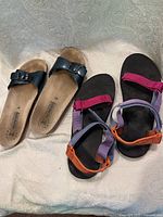 Overview of the two pairs of sandals placed side by side, showing the Mephisto black buckle sandals and the colorful Teva strap sandals