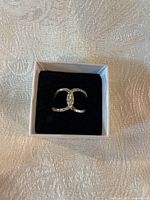 Front view of the sterling silver double hoop ring with diamond chips in a white box with black velvet cushion.