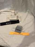 Two large crafting punches with punched paper strips showing their decorative cutout designs on a fabric background