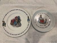 Two plates, an 8 inch Wedgwood Peter Rabbit plate and a 6 inch Wedgwood Peter Rabbit plate, displayed on a light fabric surface.