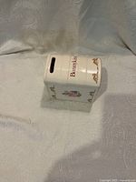 Side view showing the Bunnykins logo, floral and bunny illustrations, and coin slot on top.