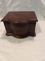 Small mahogany jewelry case with curved front view showing wood finish and shape