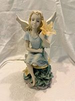 Front view of garden nymph figurine sitting holding a flower with solar light.
