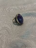 Ring shown at an angle highlighting the bezel set oval amethyst stone and split shank silver band.