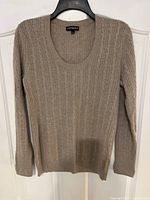 Front view of taupe cashmere sweater with cable knit design, long sleeves, and scoop neckline on hanger.