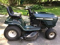 Side view showing green body, black seat, steering wheel, large rear and front turf tires, side discharge deck labeled EZ.