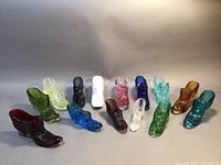 Full view of all 14 Fenton glass slippers arranged side by side showcasing various colors and patterns.