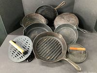 Overview of all nine cast iron pieces including pans and press plates
