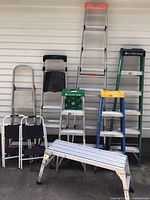 Front view of all ladders and work platform against wall, showing sizes and colors