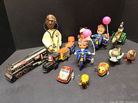 Full lot arranged showing wooden doctor sculpture and 10 tin wind-up toys of various types