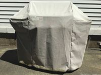 Weber grill covered with branded cover, cover shows tear and wear
