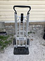 Front of folded cart showing aluminum frame, black nose plate and rear wheels