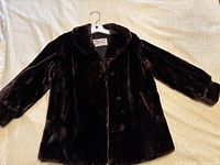 Full view of the dark brown seal fur coat laid flat showing classic design, collar, and sleeves.