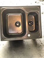 Top view of the stainless steel double basin kitchen sink showing two bowls with drains, a larger left basin and smaller right basin.