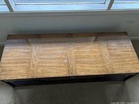 Top view of the rectangular light brown wooden coffee table showing wood grain and surface condition with moderate scratches.
