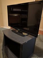 Philips 32 inch LCD TV placed on black MDF and glass TV stand, showing overall condition and setup.