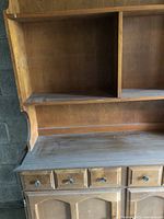 Upper section of the hutch showing open shelving with vertical divider, wooden finish with visible grain and slight wear.