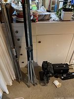 Two folded tripod screens, film projector, accessories on carpet in indoor setting.