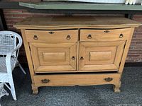 Front view of the vintage wooden sideboard with two drawers and two cabinet doors, showing wear and natural wood finish.