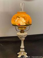 Full view of the lamp showing white porcelain base and glass milk shade with hand painted flower.