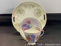 Set showing Bavaria cake plate with white flowers and handles, standing upright behind Paragon floral teacup and saucer in front.