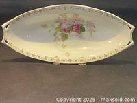 Full view of oval porcelain bowl with pink floral decoration and pattern along rim.