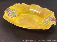 Front angle showing yellow mottled finish with floral and fruit hand painted designs on handles on either side. Scalloped edges visible.